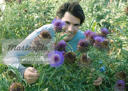 Man smiling, behind thistle flowers