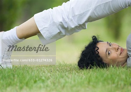 Young woman doing plow pose outdoors, smiling at camera