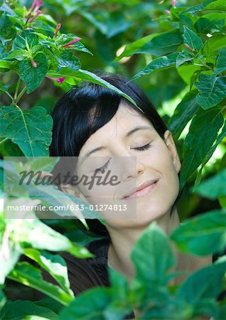 Femme debout parmi les feuilles, tête et épaules