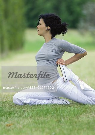Young woman stretching on grass