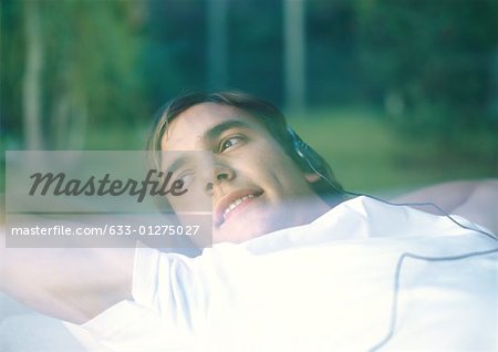 Man lying down, listening to headphones