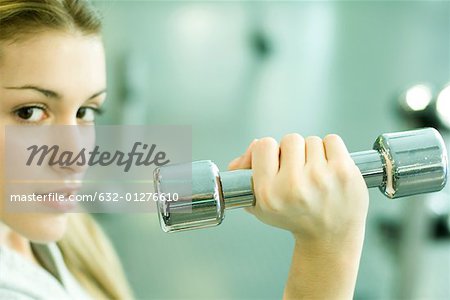 Woman holding up dumbbell, partial view