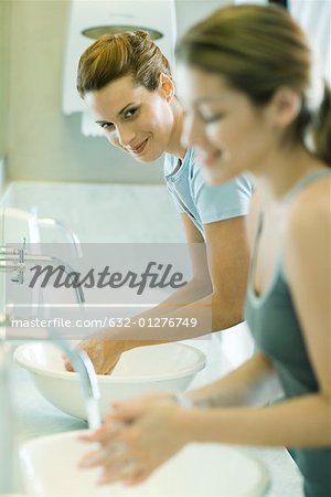 Deux femmes se laver les mains dans les éviers