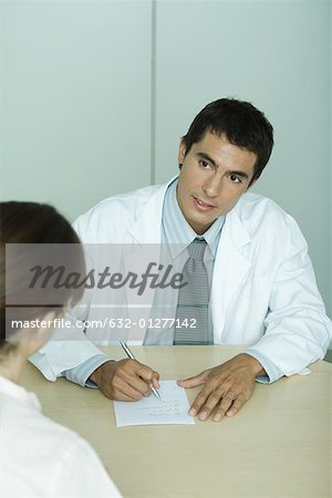 Doctor sitting across from patient, taking notes
