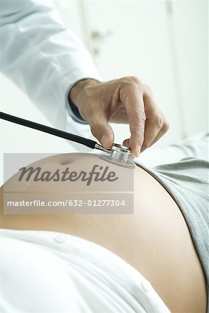 Doctor holding stethoscope to pregnant woman's stomach