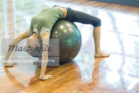 Jeune femme faisant backbend sur boule de remise en forme