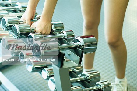 Woman picking up dumbbells