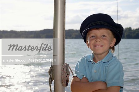 Petit garçon avec un chapeau de capitaine est debout à côté d'une tige, gros plan