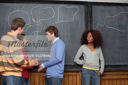 Four young people standing in front of a blackboard with empty speech balloons