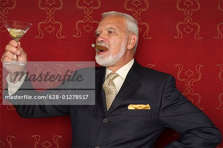 Mature businessman holding a glass of martini and a cigar