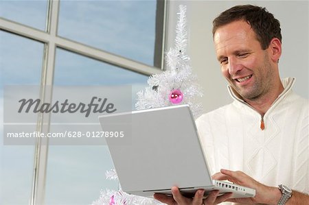 Aide d'un ordinateur portable en face d'un arbre de Noël blanc