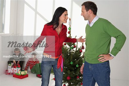 Mère et père faisant valoir devant l'arbre de Noël, les enfants assis dans le coin