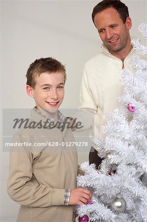 Vater und Sohn neben einem weißen Weihnachtsbaum