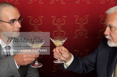 Two businessmen clinking glasses with martini