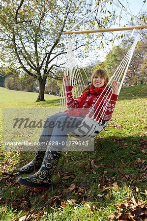 Young woman in warm clothing sitting on a hammock