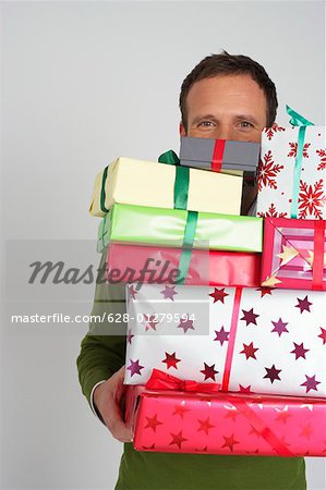 Homme portant une pile de Noël présente