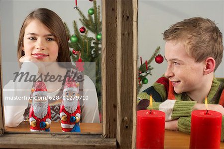 Fille et garçon à la recherche d'une fenêtre, arbre de Noël en arrière-plan