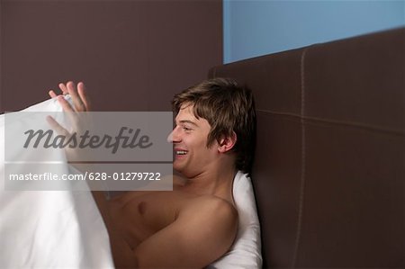 Young naked man looking under the blanket