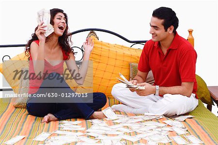 Young couple sitting on the bed and sharing paper currency