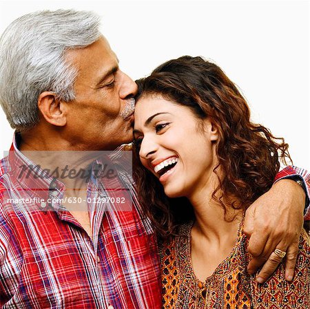 Close-up of a senior man kissing his daughter on the forehead