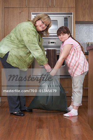 Mother and Daughter with Garbage Bag in Kitchen