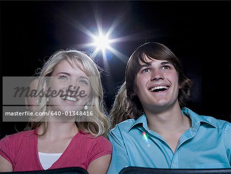 Boy and girl watching film at movie theater smiling