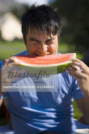 Junger Mann beißt ein Stück einer Wassermelone