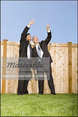 Vue d'angle faible de deux hommes d'affaires pointant vers le ciel