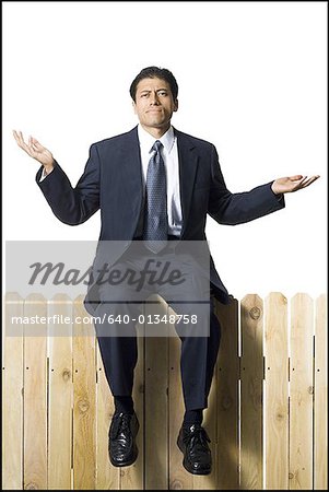 Businessman on wooden fence shrugging