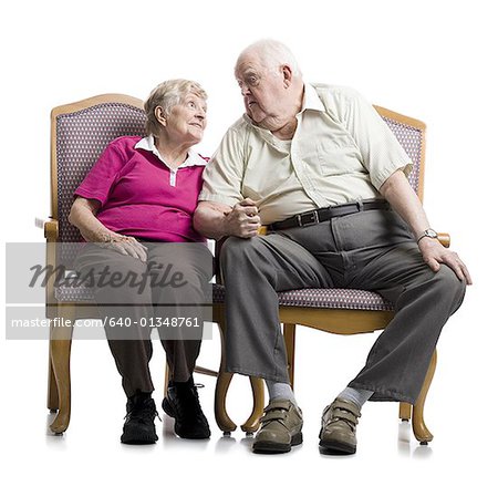 Senior couple sitting on an armchair looking at each other