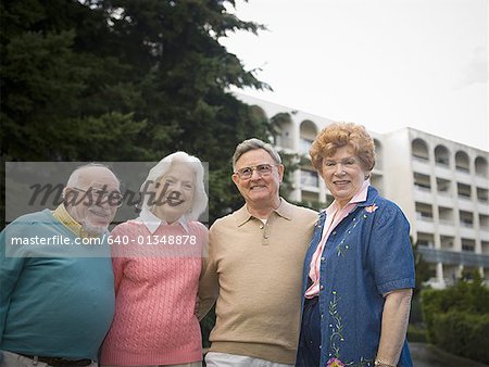 Portrait de deux couples seniors souriant avec leurs bras autour de l'autre