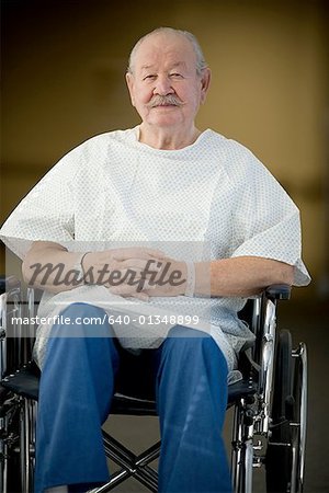 Male patient sitting in a wheelchair with his hands clasped
