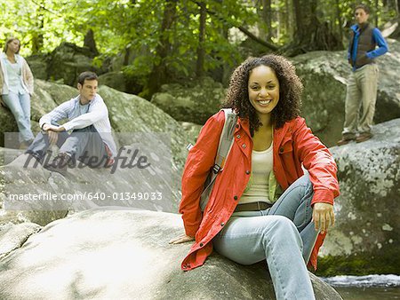 Portrait of a young woman sitting on a rock and smiling