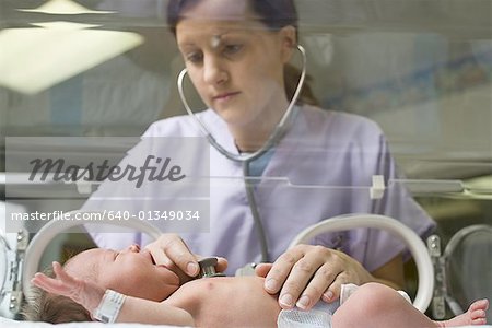 Weibliche Krankenschwester untersuchen ein Neugeborenes mit einem Stethoskop