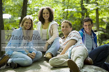 Portrait de deux jeunes femmes et deux jeunes hommes assis sur un rocher et souriant