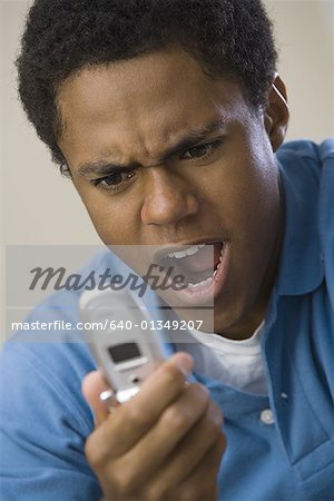 Close-up of a teenage boy shouting at a mobile phone
