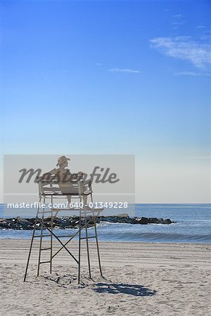 Rear view of a young man sitting on a lifeguard chair