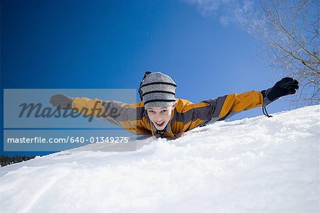 Portrait of a boy lying in snow with his arm outstretched