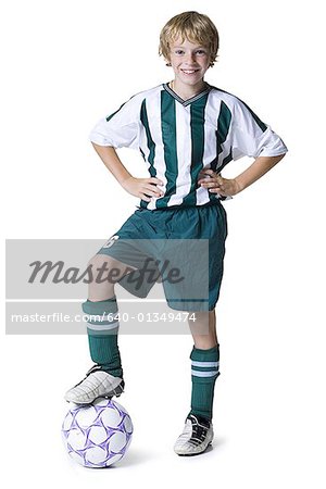 Portrait d'un garçon avec son pied sur un ballon de soccer