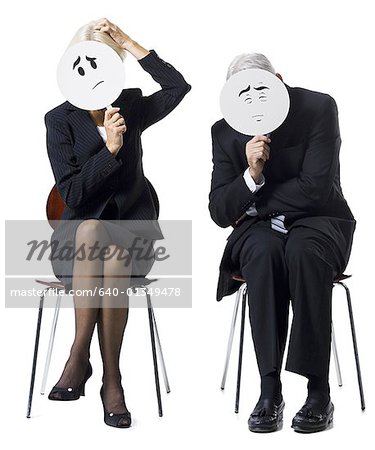 Businessman and businesswoman holding expression masks