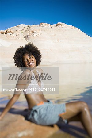 Profile of a young woman sitting on a rock and smiling