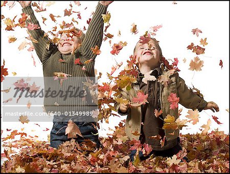 Jeunes enfants qui jouent dans les tas de feuilles mortes