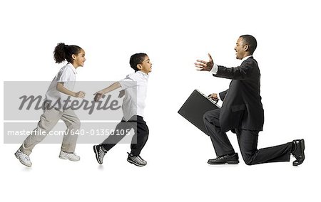 Boy and girl running toward kneeling businessman