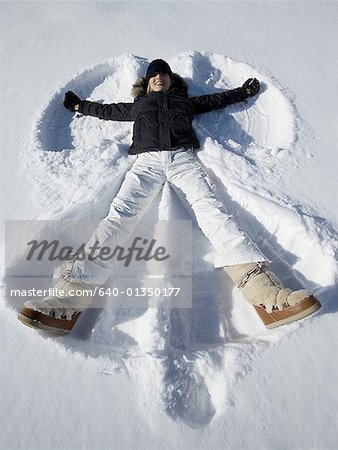 High angle view of a young woman lying in snow making a snow angel