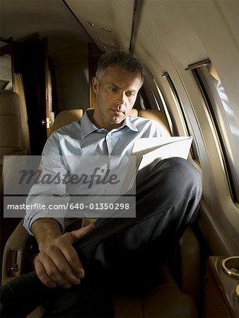 Un homme lisant un journal dans un avion