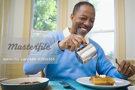Close-up of a senior man pouring syrup on his waffle