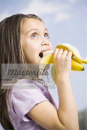 Jeune fille mange banane Photographie de stock Masterfile