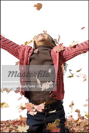 Jeune fille jouant dans les feuilles mortes