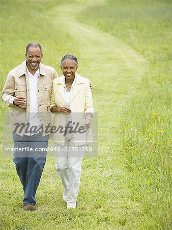 Vue grand angle sur un homme senior et une senior femme qui marche dans un champ