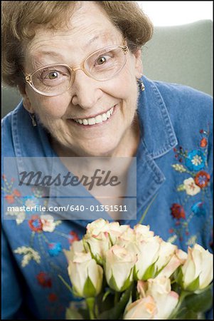 Portrait d'une femme senior tenant un bouquet de rose blanche et souriant